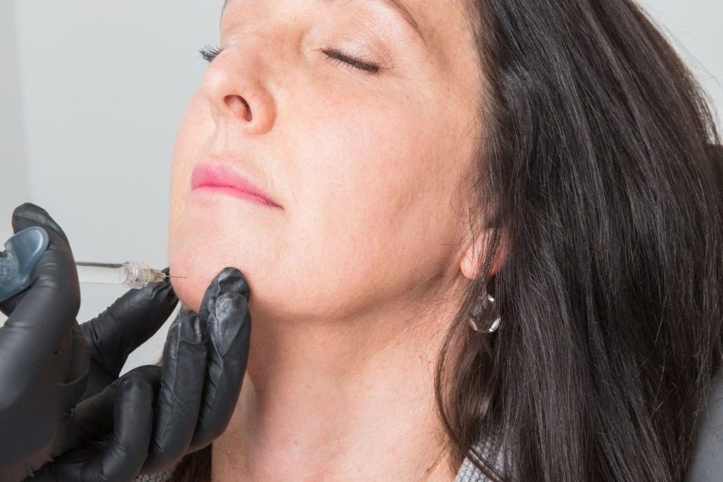 A woman getting chin filler injected by a professional.